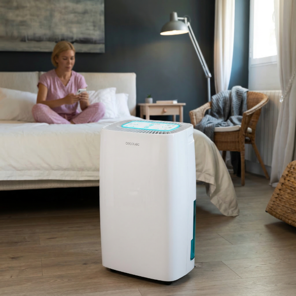 Deshumidificador silencioso Cecotec Big Dry 4000 funcionando en un dormitorio mientras una persona usa el móvil en la cama.