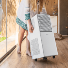 Persona moviendo fácilmente el aire acondicionado portátil Cecotec gracias a sus ruedas 360º y asas.