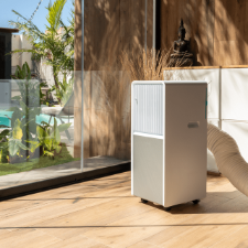 Aire acondicionado portátil Cecotec 9550 instalado en un salón luminoso con su kit de ventana.