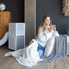 Mujer en el sofá con manta y café disfrutando de la bomba de calor del Cecotec 9550.