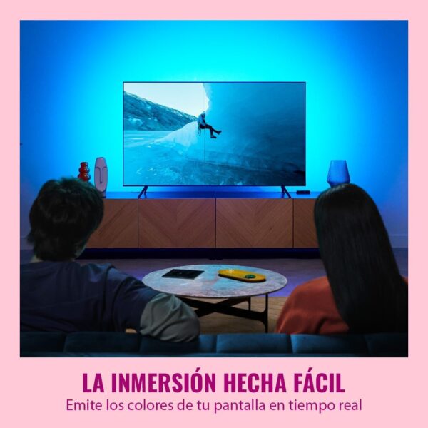 Dos personas sentadas en el salón viendo una pantalla de televisión rodeada de una luz ambiental azul intensa proyectada hacia la pared.