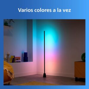 Lámpara de pie Philips proyectando múltiples colores simultáneos en degradado cyan, rosa y amarillo sobre la pared.