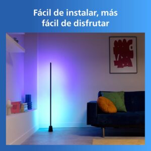 Lámpara de pie inteligente Philips proyectando luz morada y azul en la esquina de un salón moderno con un sofá azul.