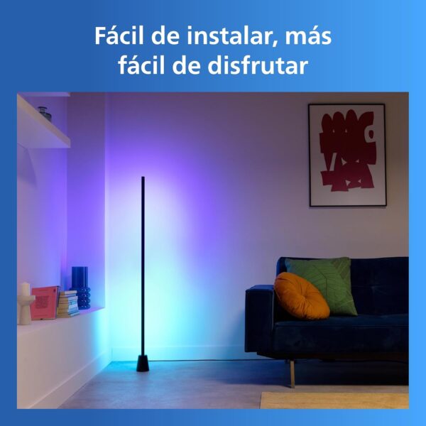 Lámpara de pie inteligente Philips proyectando luz morada y azul en la esquina de un salón moderno con un sofá azul.